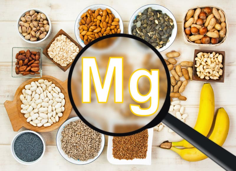 image of magnesium element symbol in magnifying glass with magnesium rich foods in the background